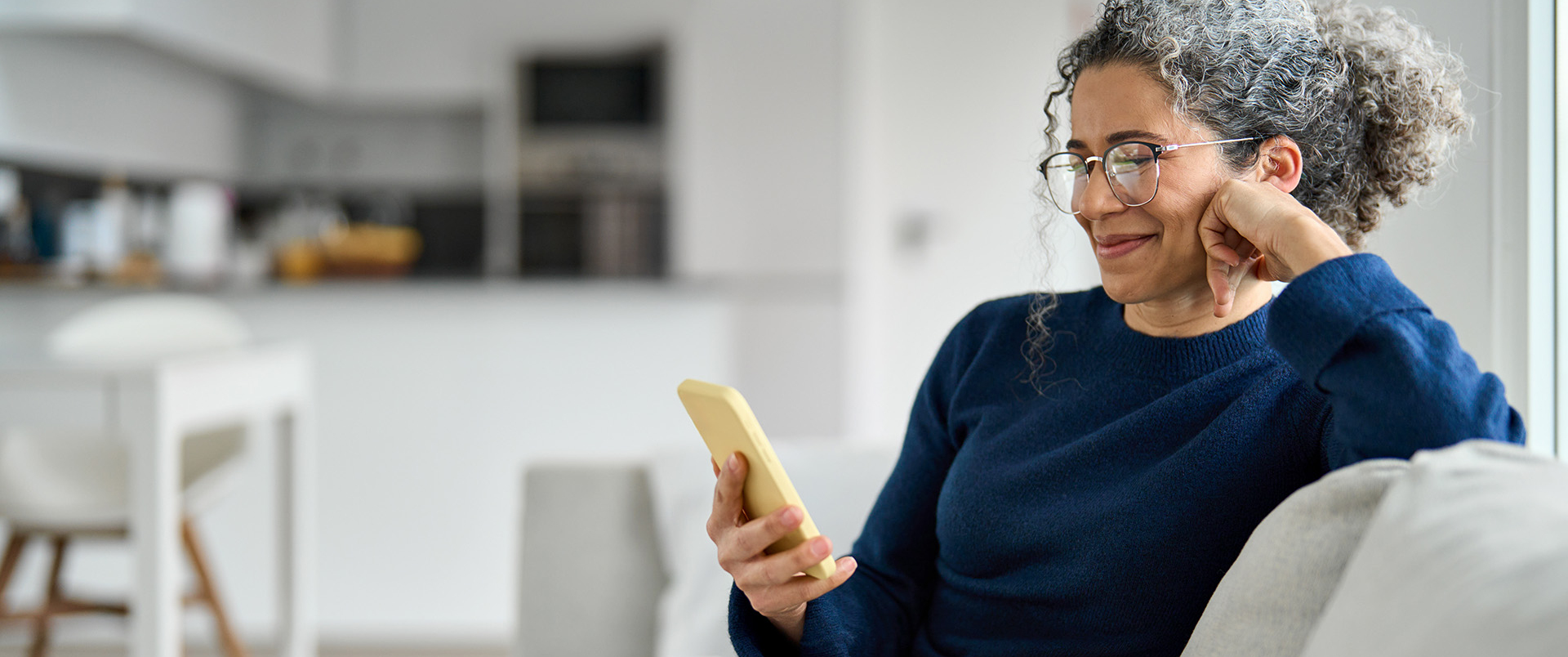Eine Frau sitzt auf dem Sofa und nutzt ihrt Smartphone