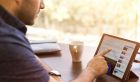 Ein Mann sitzt mit einem i-Pad am Schreibtisch